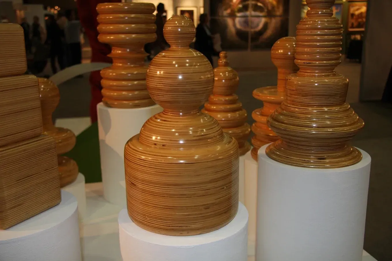 A group of wooden sculptures are sitting on white stands