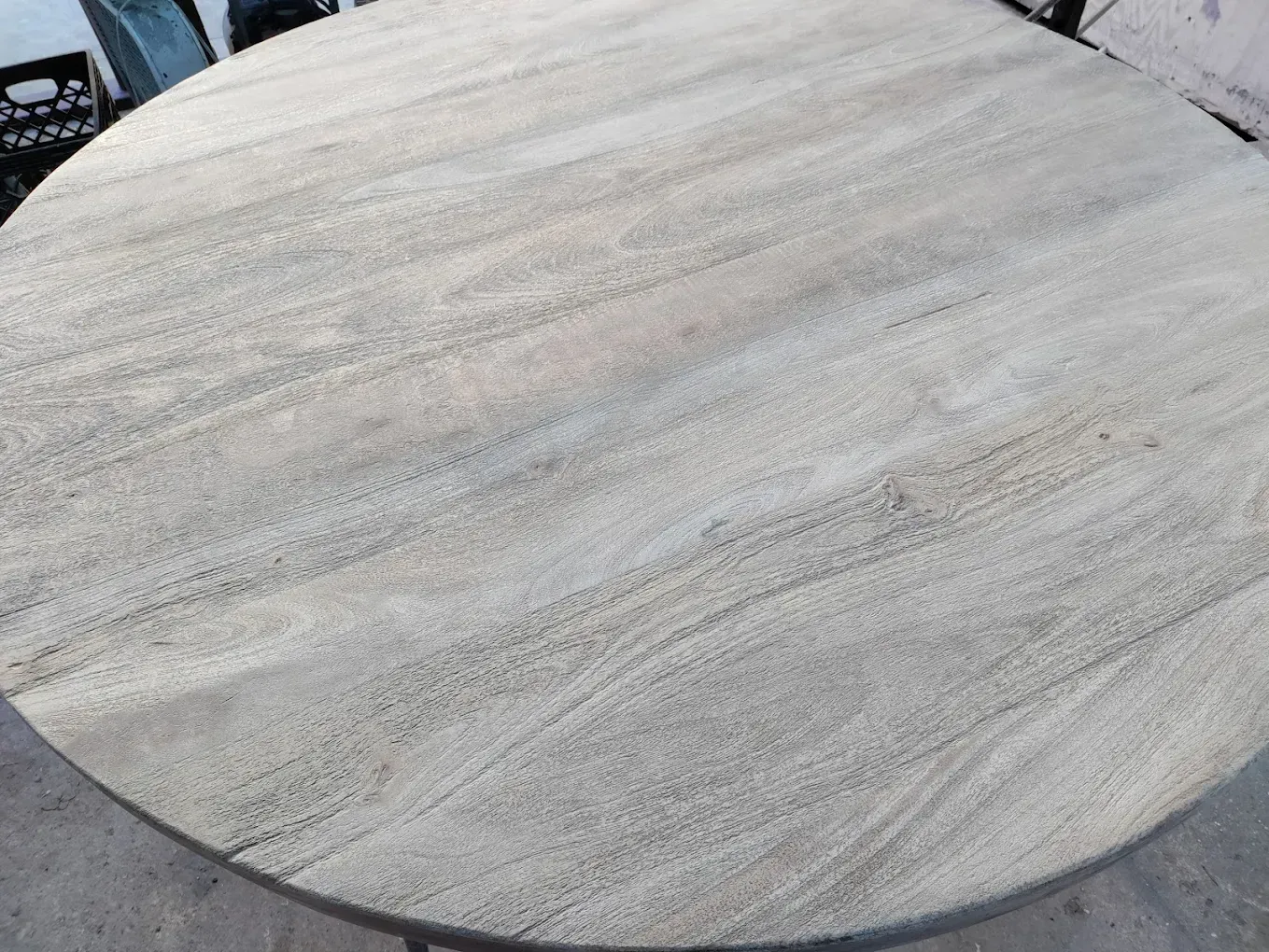 A round wooden table with a metal frame is sitting on the ground.