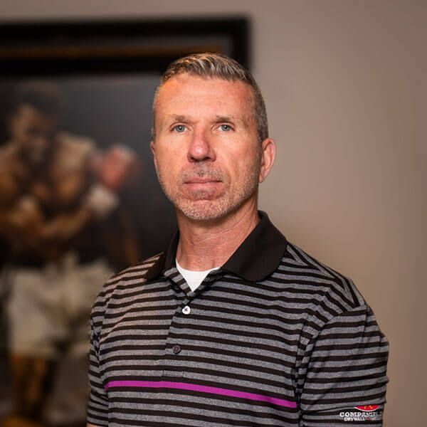 Man in striped polo shirt, neutral expression, standing near an artwork of a boxer.