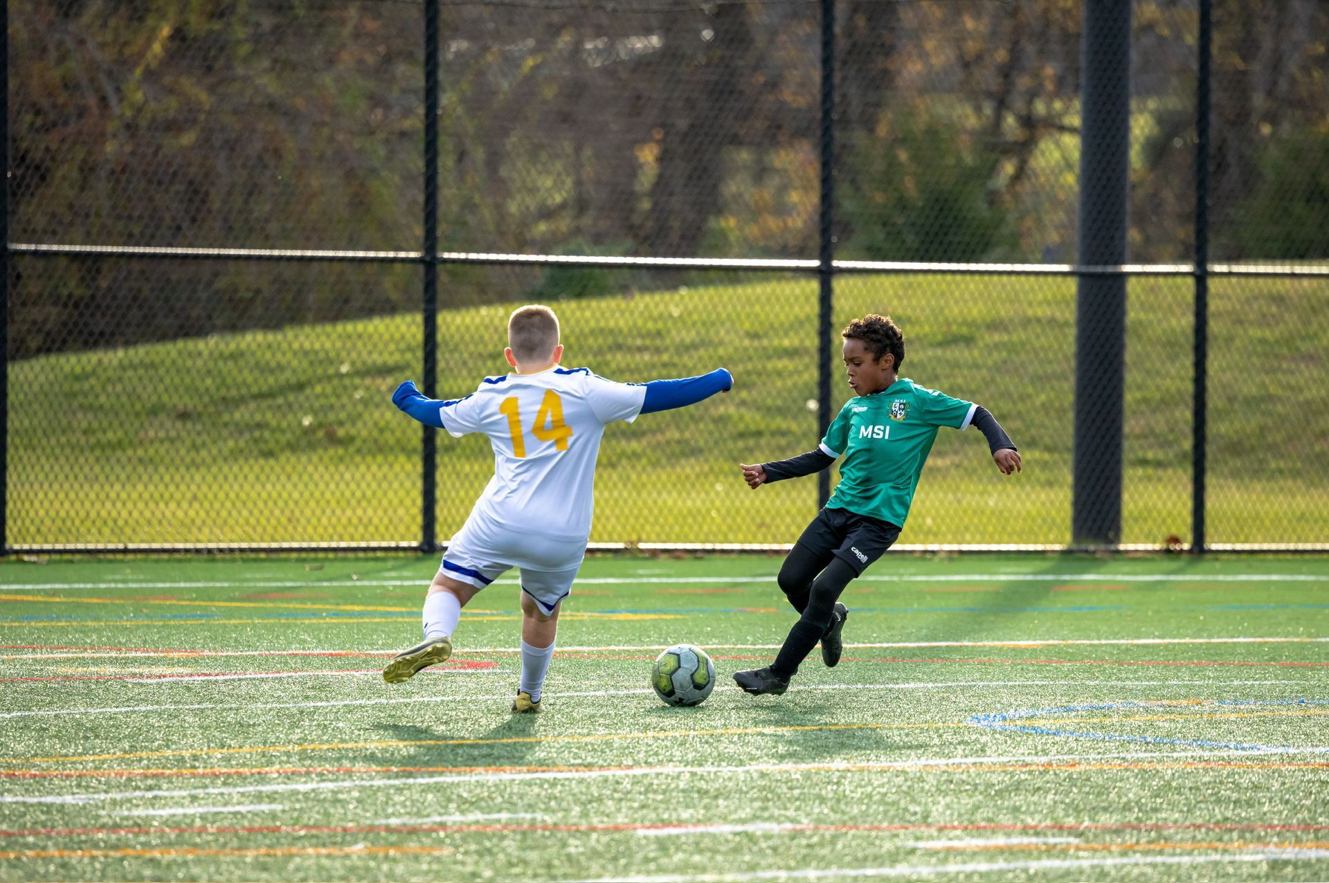 MSI travel player in a green jersey strikes the ball as an opponent in closes down.