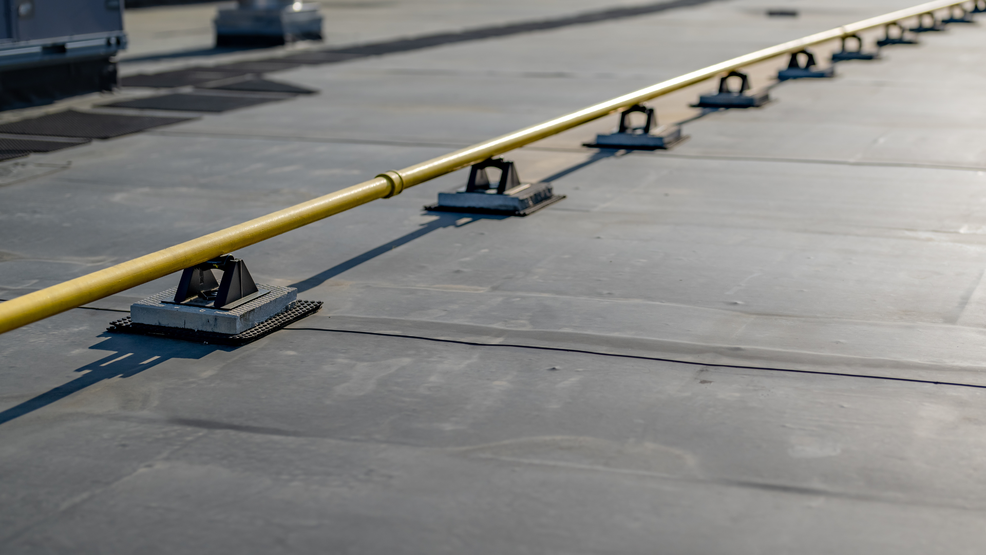 A yellow pipe is sitting on top of a black roof.