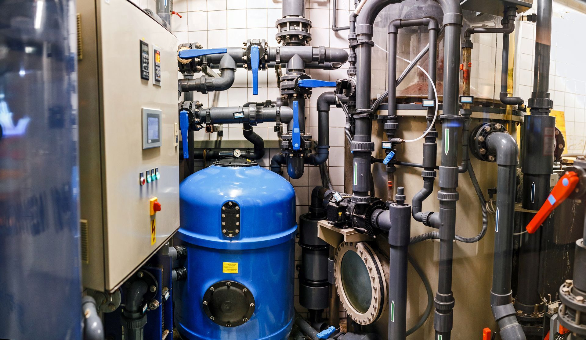 A room filled with lots of pipes and a blue tank.