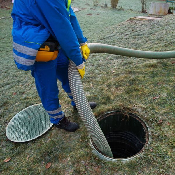 A man is pumping water into a manhole with a hose.