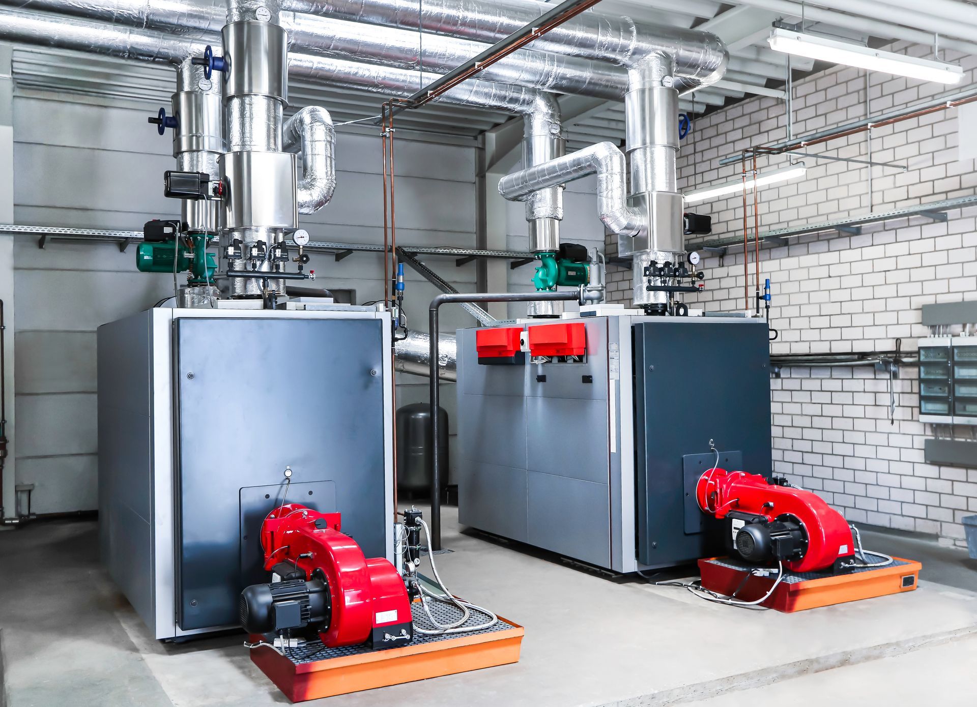 Two boilers are sitting next to each other in a room.