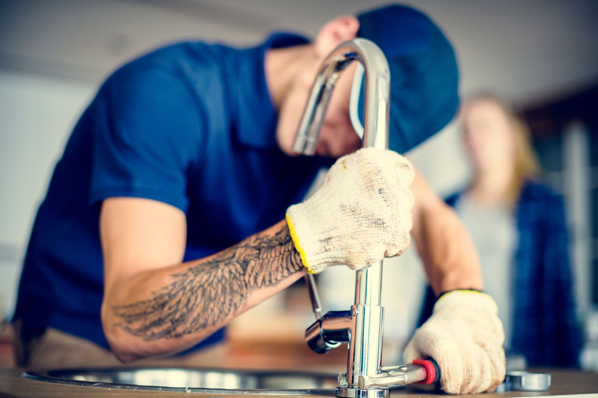 A man is fixing a sink faucet with a wrench.