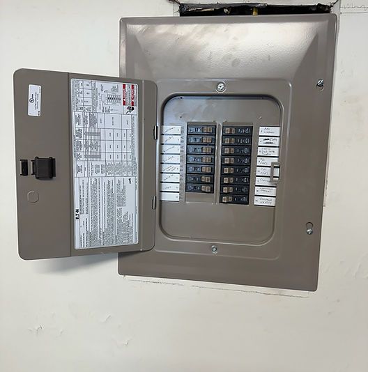 Open electrical breaker panel with gray cover on a white wall.