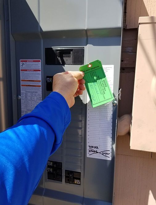 Hand holding a green access card near an outdoor electrical meter box