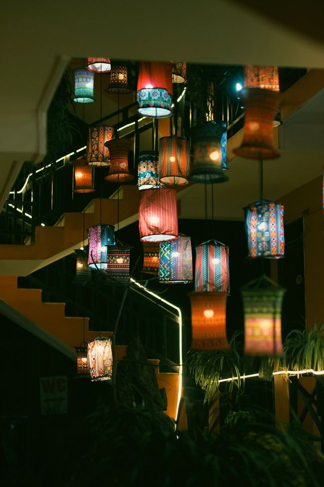 Colorful hanging lanterns glowing on a staircase in a dim indoor space