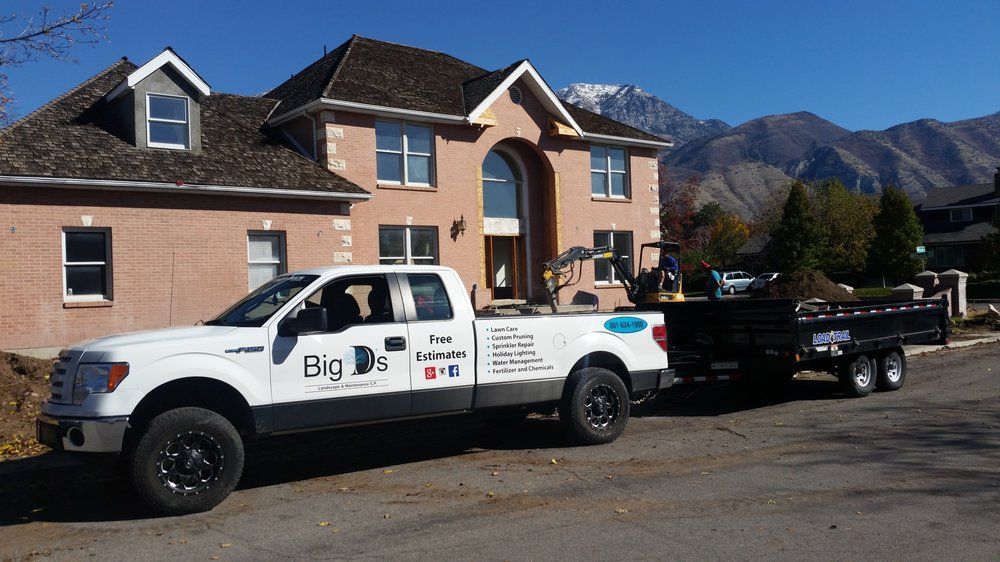 White truck and trailer in front of a house. Mountains in the background. The truck has 