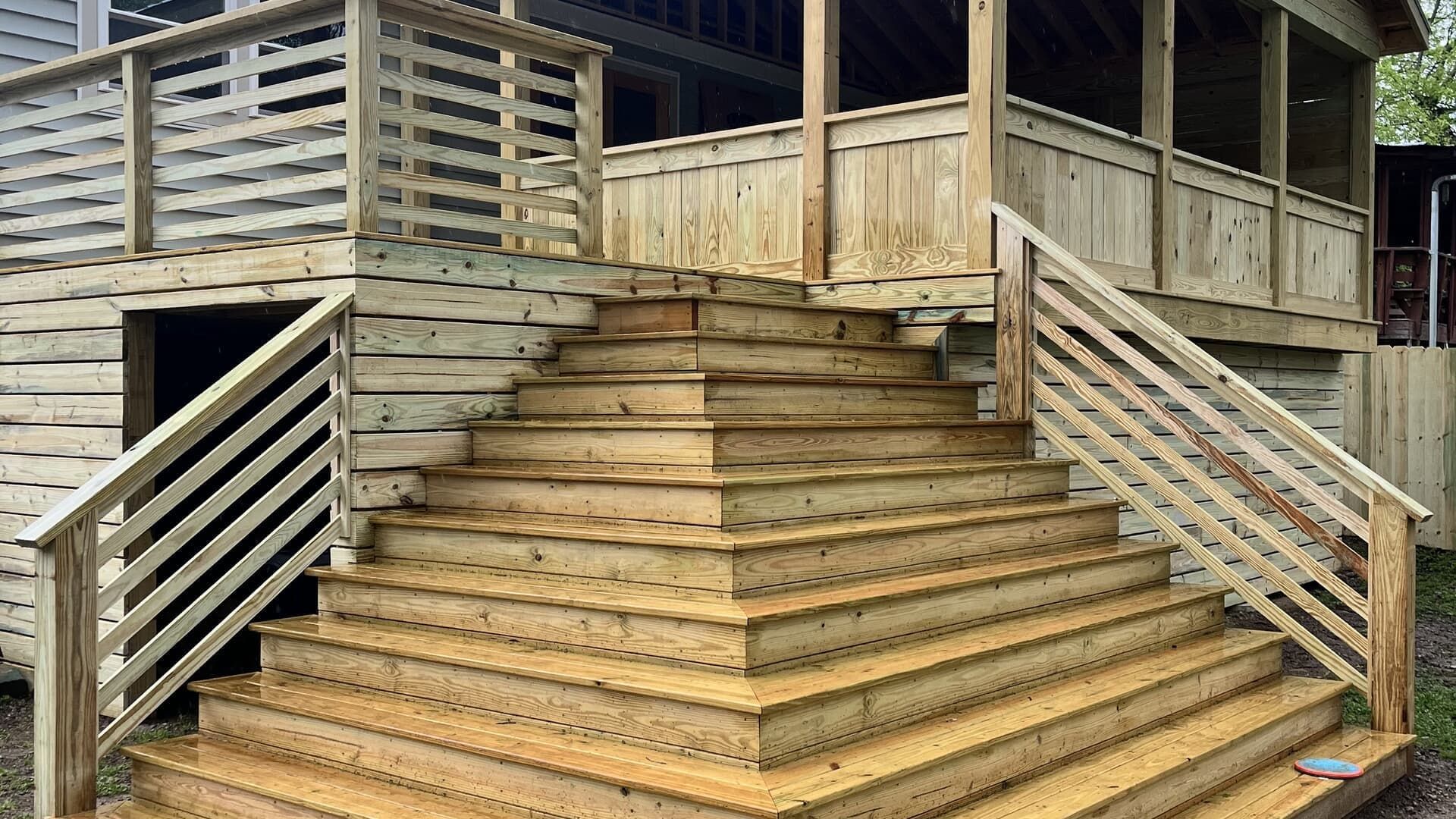 Wooden stairs leading to a covered porch; wood railing on either side.