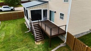 Backyard deck and screened-in porch connected to a beige house, brown deck, stairs to lawn, metal roof.