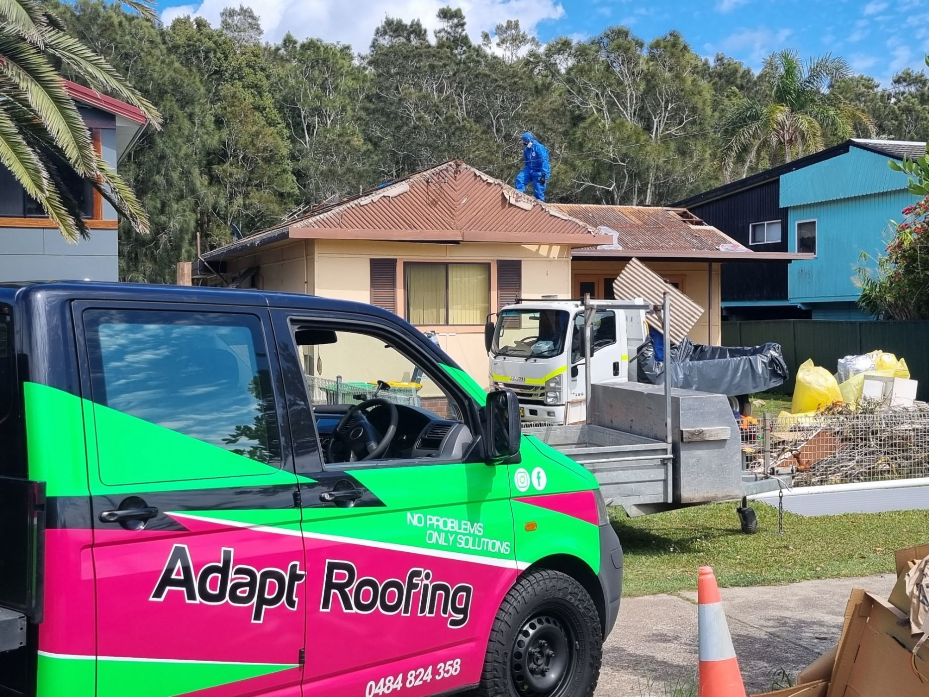 Two men are working on a tiled roof.