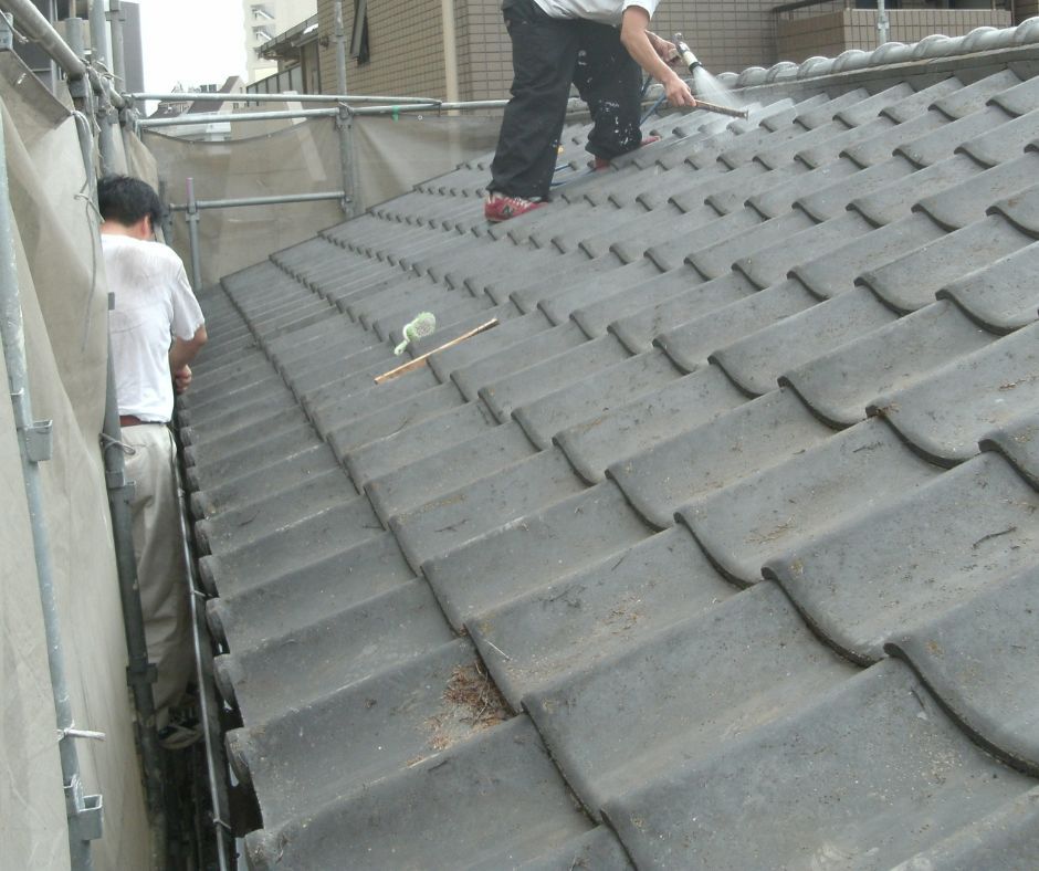 Roofing contractor cleaning and maintaining the tiled roofing