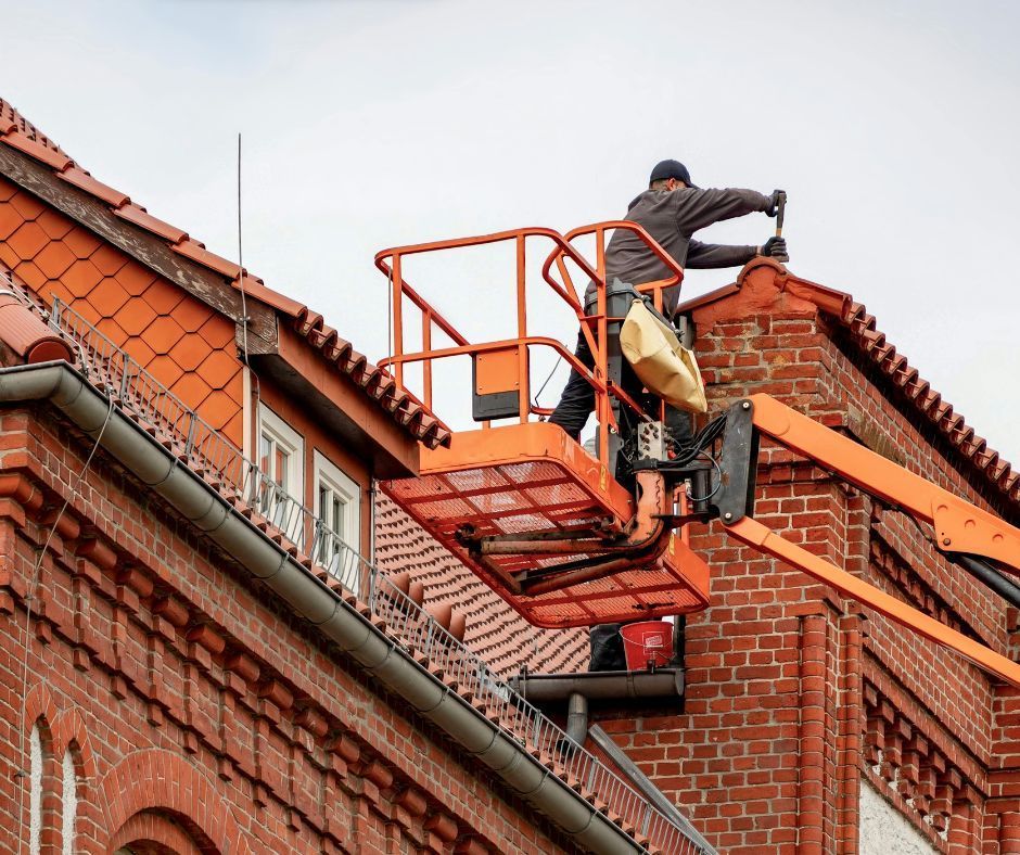 Professional roofer on a lift cleaning the roofing and gutters