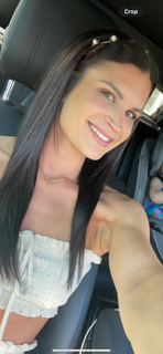 A woman is taking a selfie in the back seat of a car.