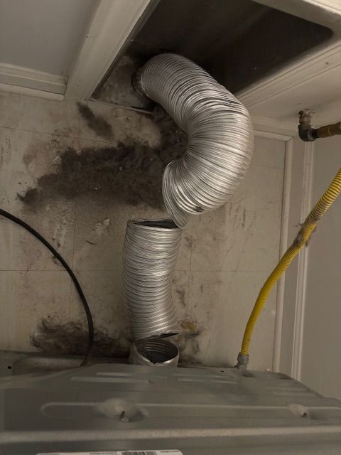 A dryer vent hose is coming out of a hole in the ceiling.