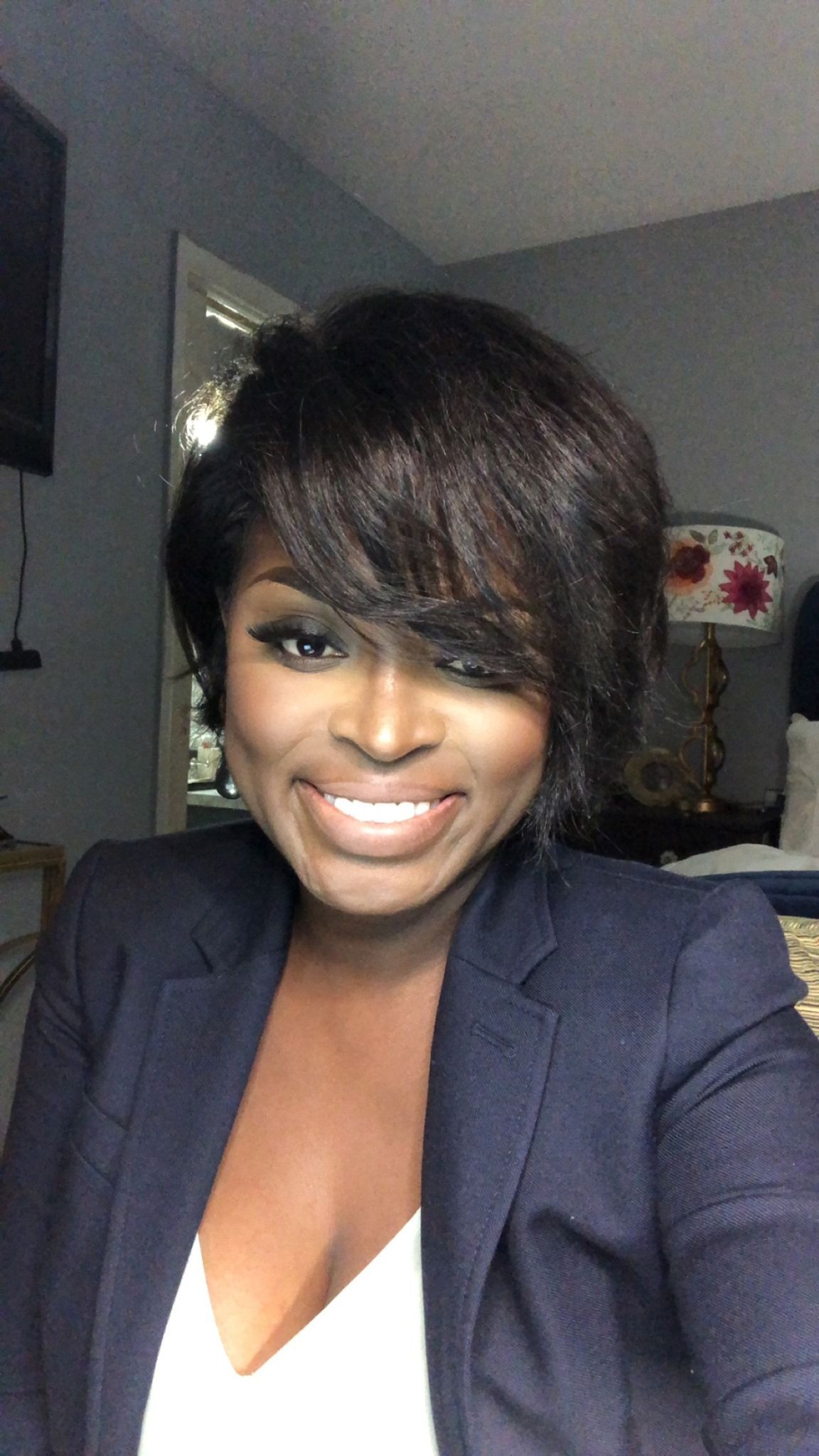 A woman in a blue jacket and white shirt is smiling for the camera.