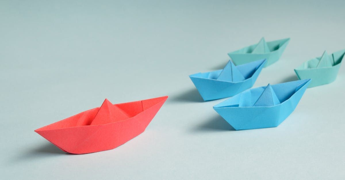 A red paper boat is leading a row of blue paper boats.