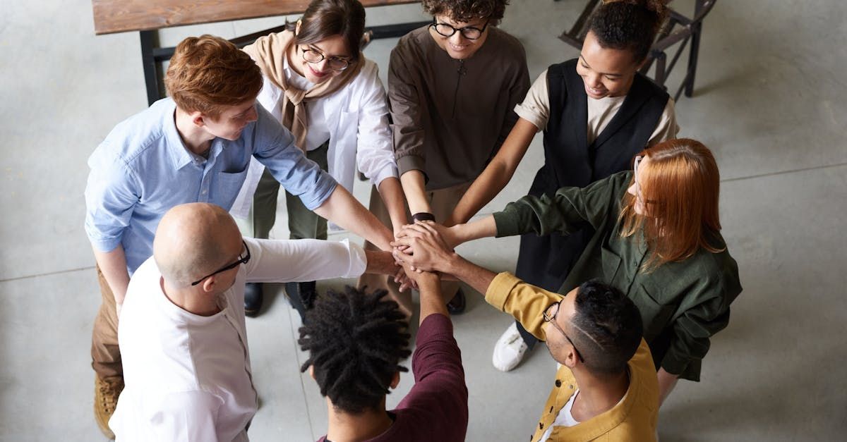 A group of people are putting their hands together in a circle.