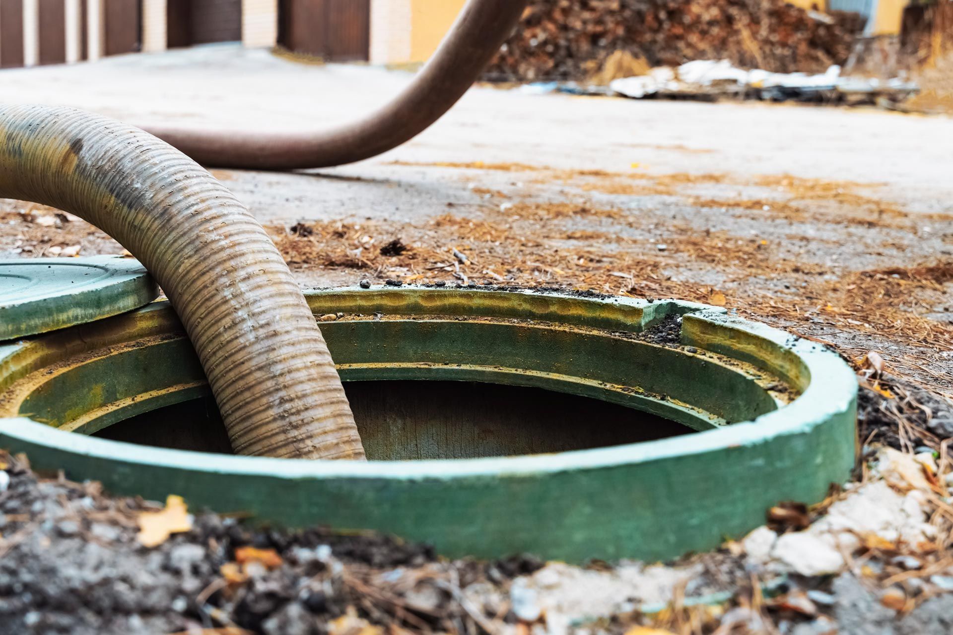 A hose enters an open green septic tank