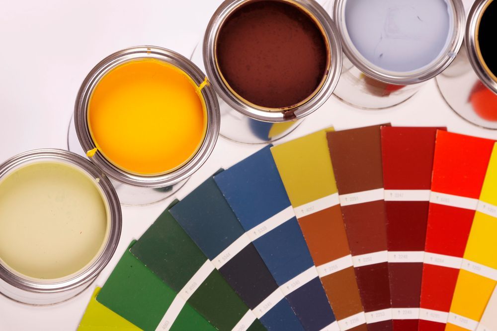 Barattoli di vernice e un campionario di colori con campioni di vernice dai colori vivaci: giallo, marrone, blu, verde e rosso.