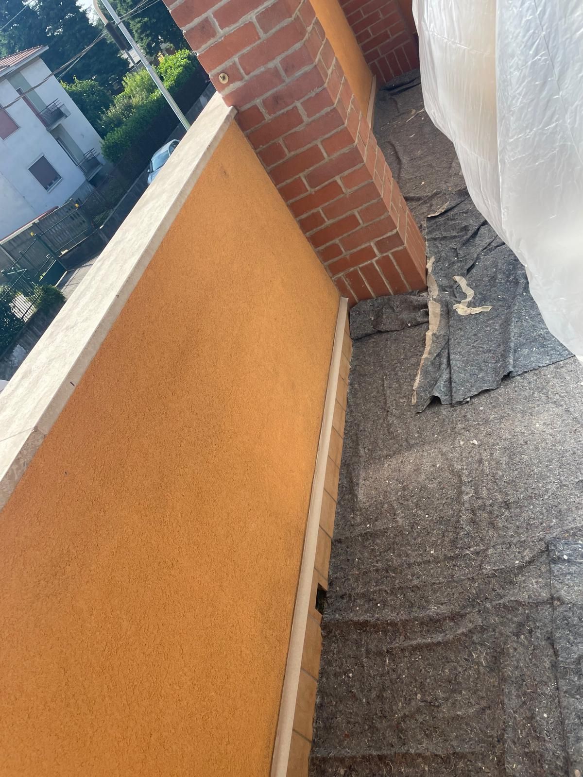 Passerella sul tetto con parete arancione, angolo in mattoni e materiale di copertura grigio strappato lungo il bordo.
