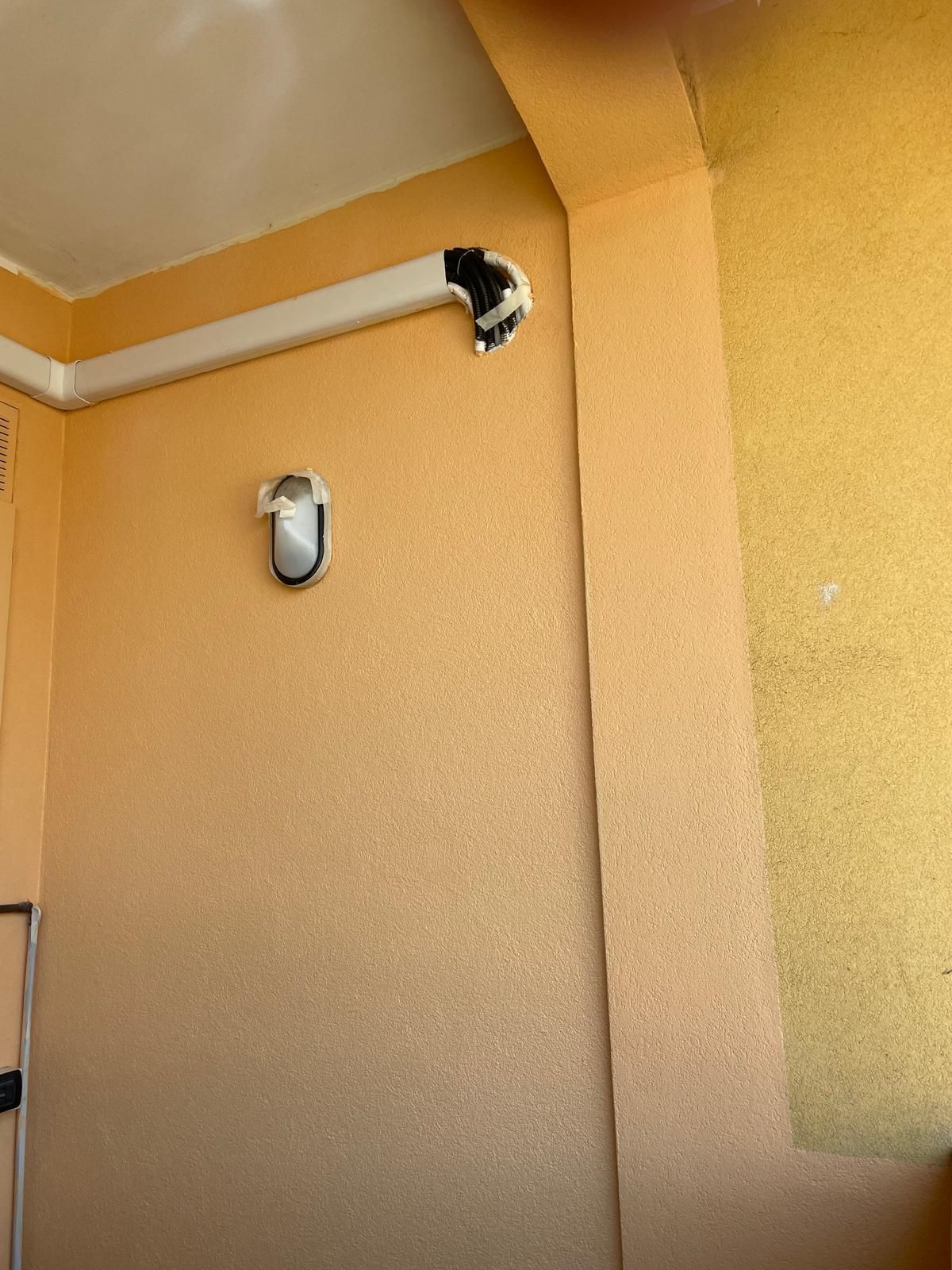 Angolo parete-soffitto beige con due apparecchi a parete, un dispositivo nero vicino al soffitto e uno bianco in basso.