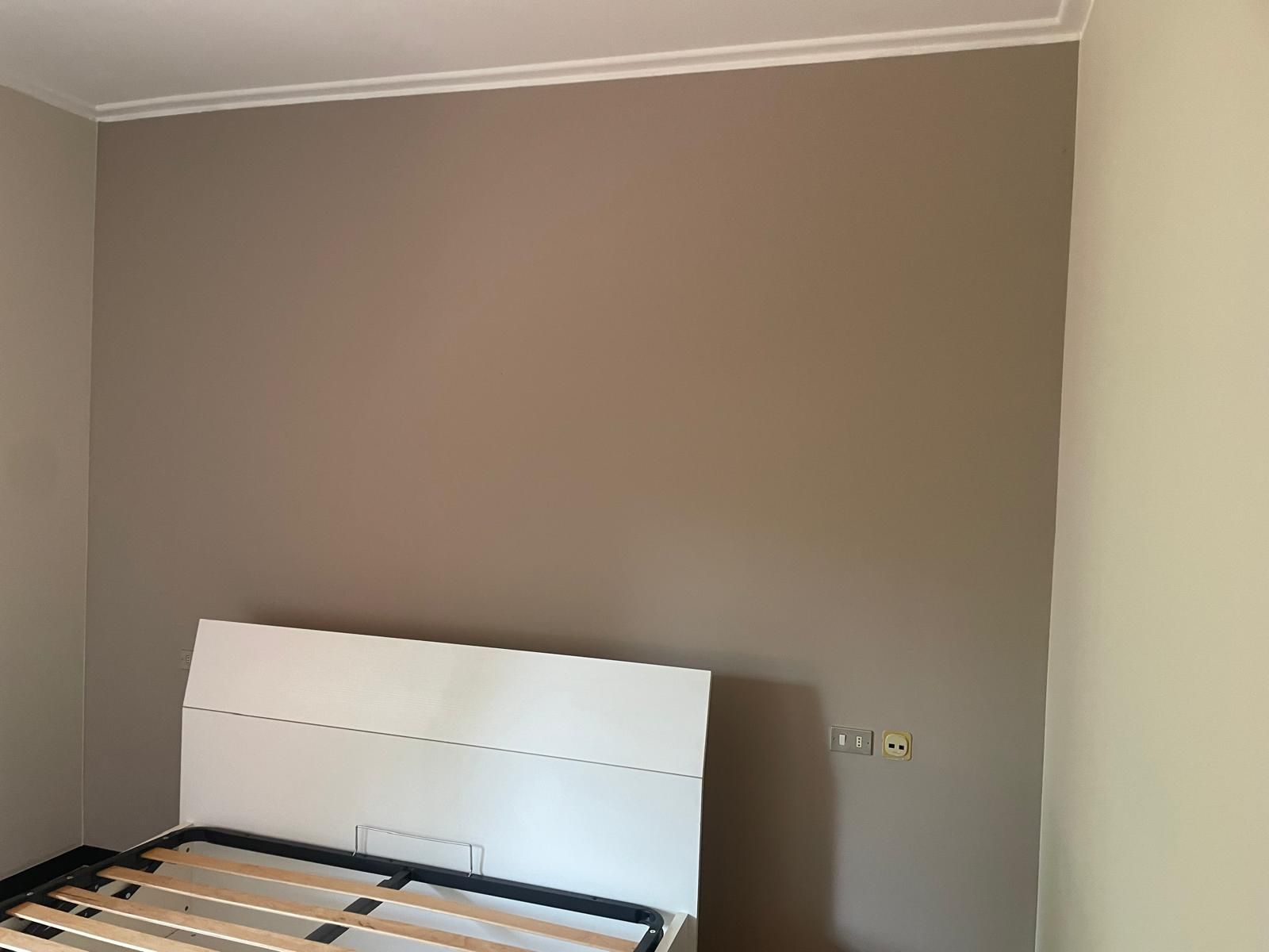 Struttura del letto parzialmente assemblata contro una parete beige della camera da letto.