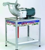 Snow cone machine on a metal table, with a silver ice shaver and a green motor.