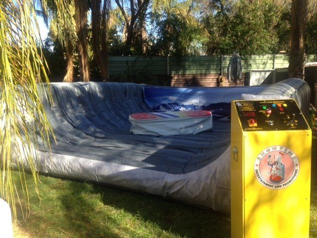 A large inflatable amusement ride with a raised platform and control panel on a grassy lawn.