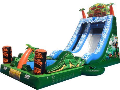 Inflatable green and blue water slide with alligator and jungle-themed details; palm trees and a pool are included.