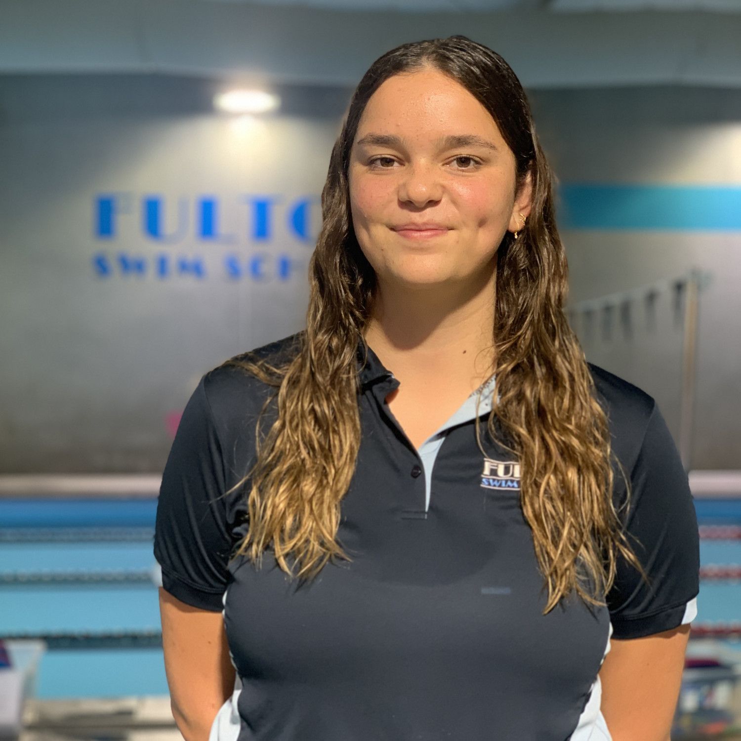 A woman is smiling in front of a swimming pool.