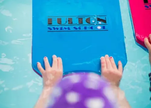 A pink float is sitting on top of a blue float in a pool.