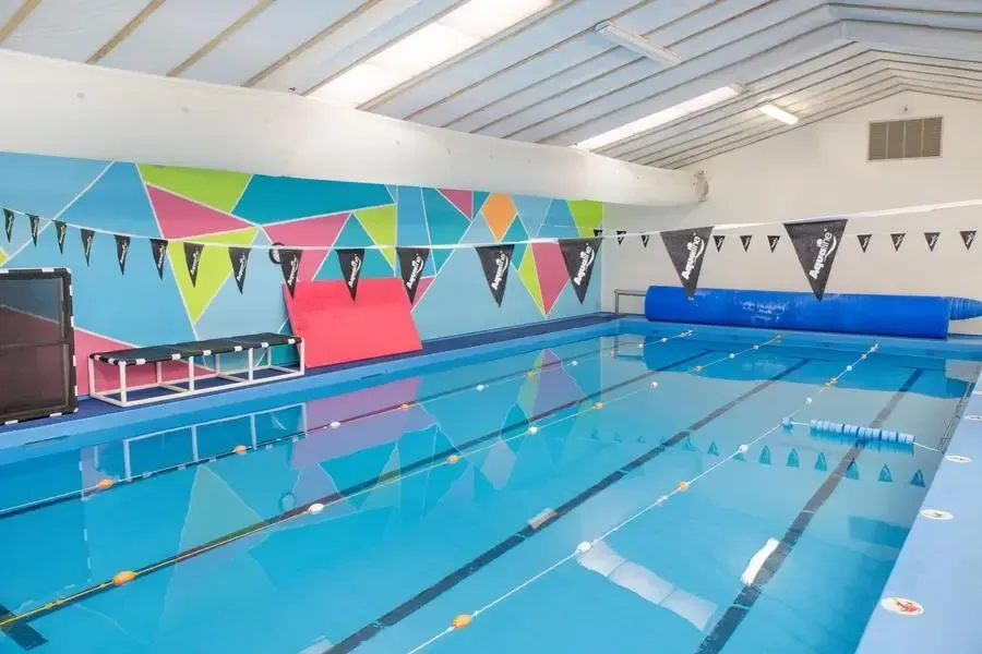 A woman is giving a child a high five in a swimming pool.