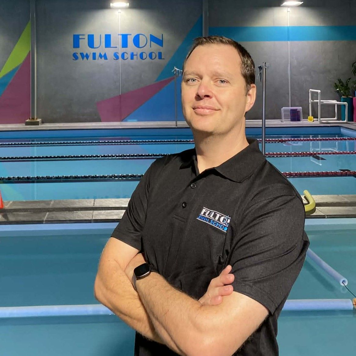 A woman is smiling in front of a swimming pool.