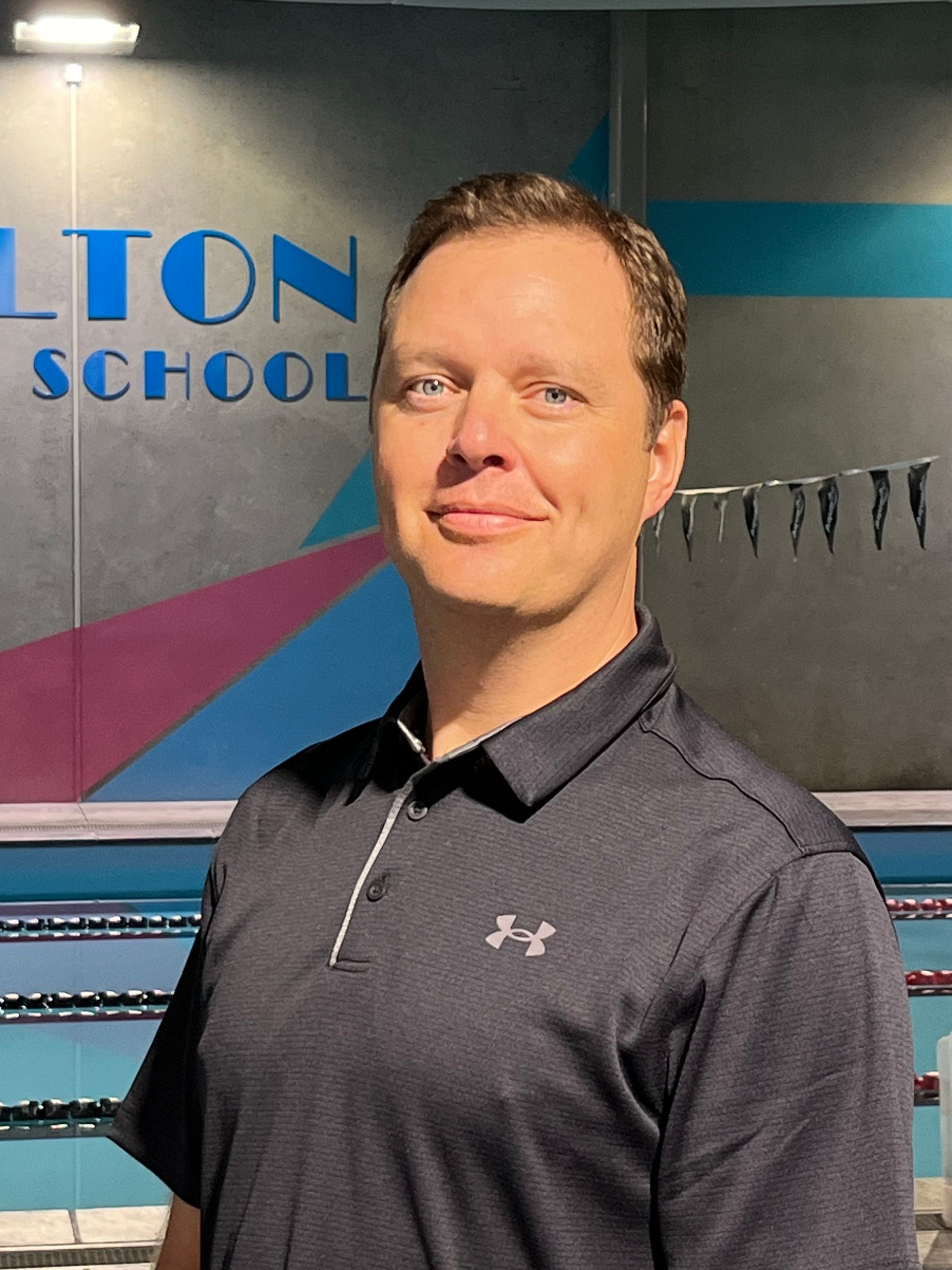 A woman is smiling in front of a swimming pool.