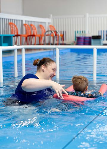 A person is holding a blue board in a swimming pool.