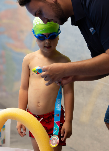 A woman is giving a child a high five in a swimming pool.