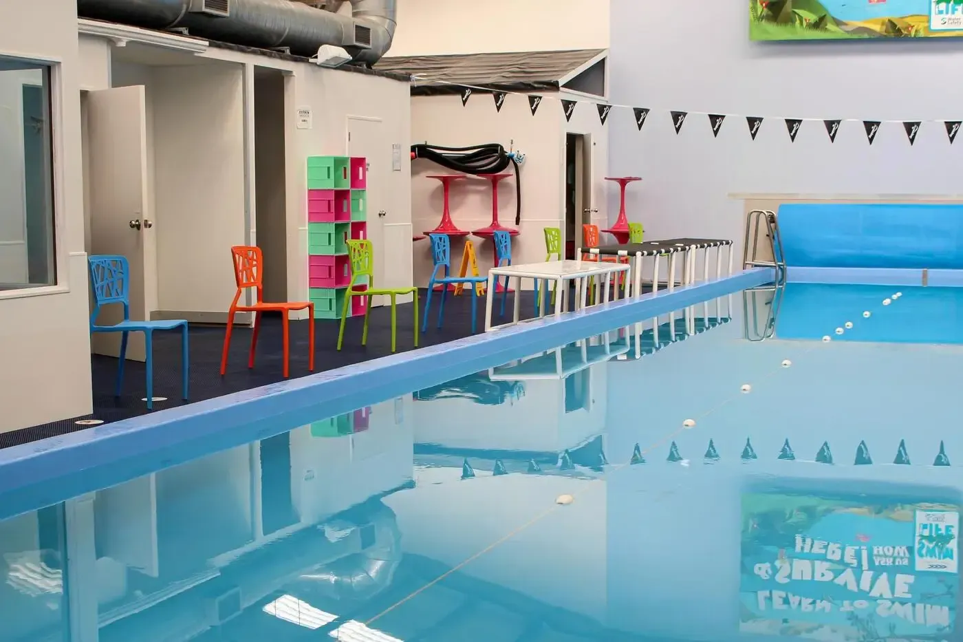 A group of people are swimming in a large indoor swimming pool.