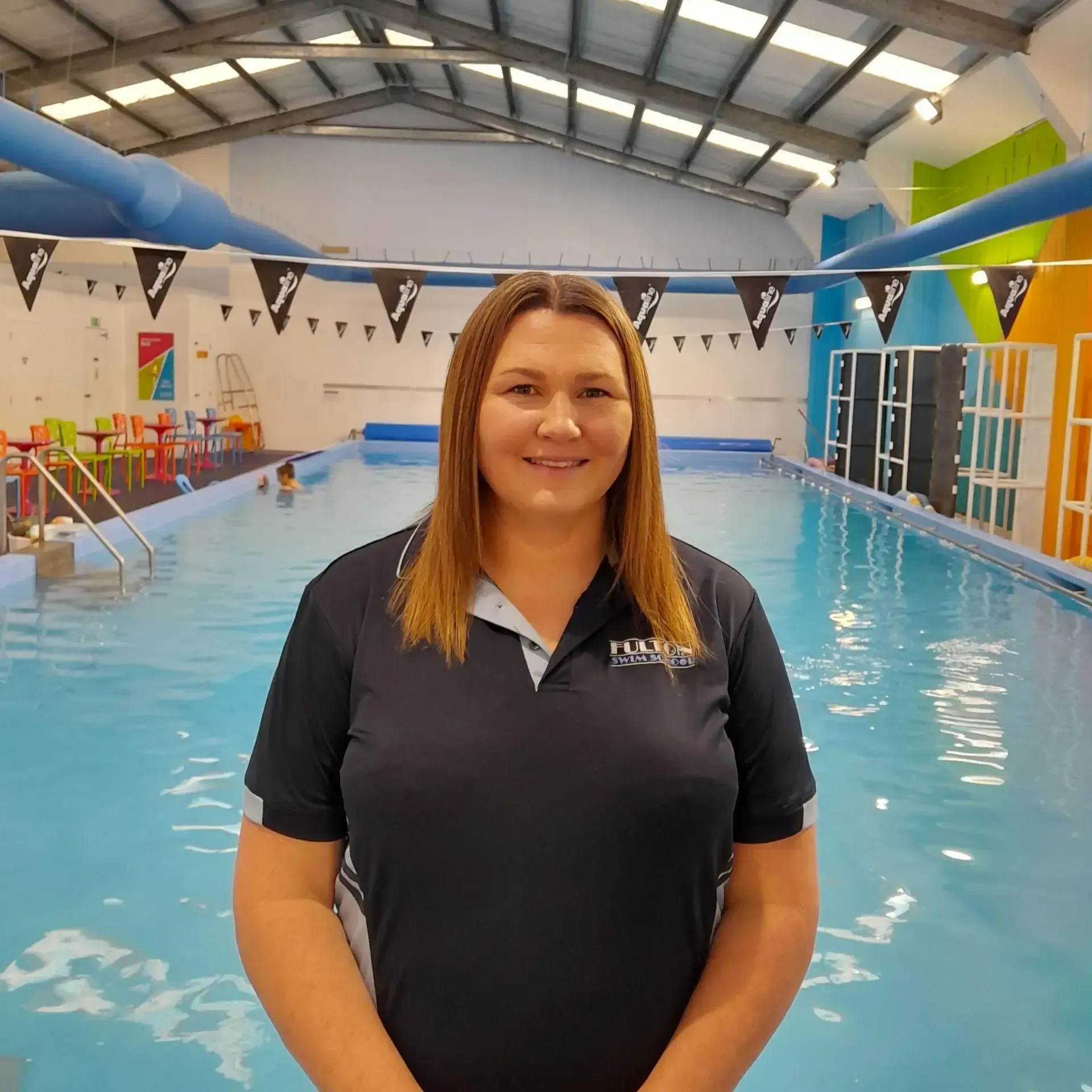 A woman in a black shirt is smiling in front of a pool