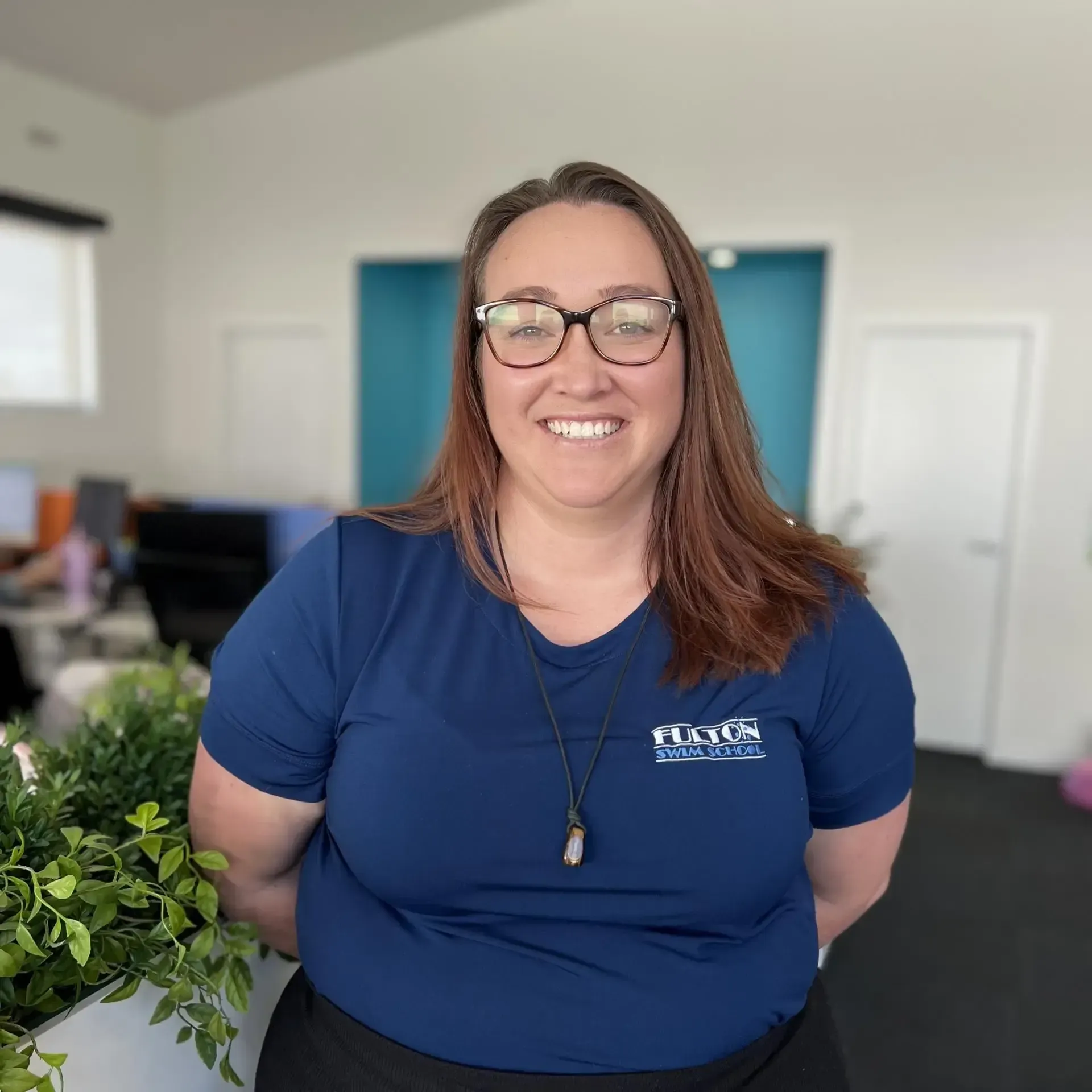 A woman wearing glasses and a blue shirt is smiling for the camera.