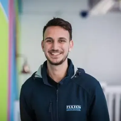 A man with a beard is wearing a blue jacket and smiling for the camera.