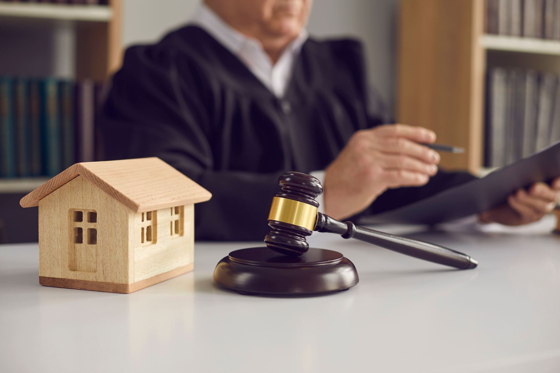 A judge is sitting at a table with a wooden house and a gavel.