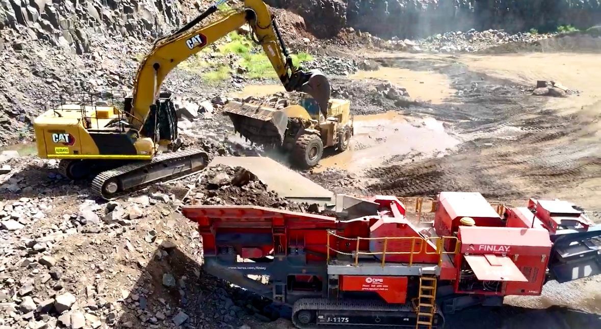 Excavator Loading Rock Into a Red and Black Rock Crusher at a Quarry — D&S Quarries in Lansdowne, NT
