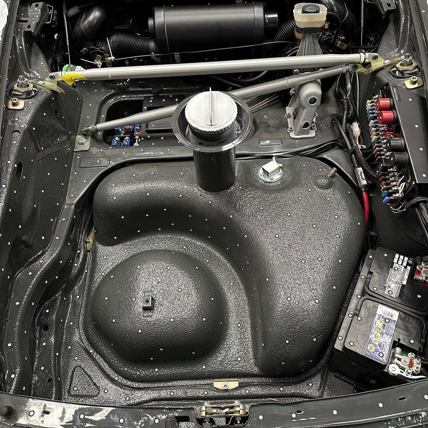 The inside of a car with a fuel tank and a battery