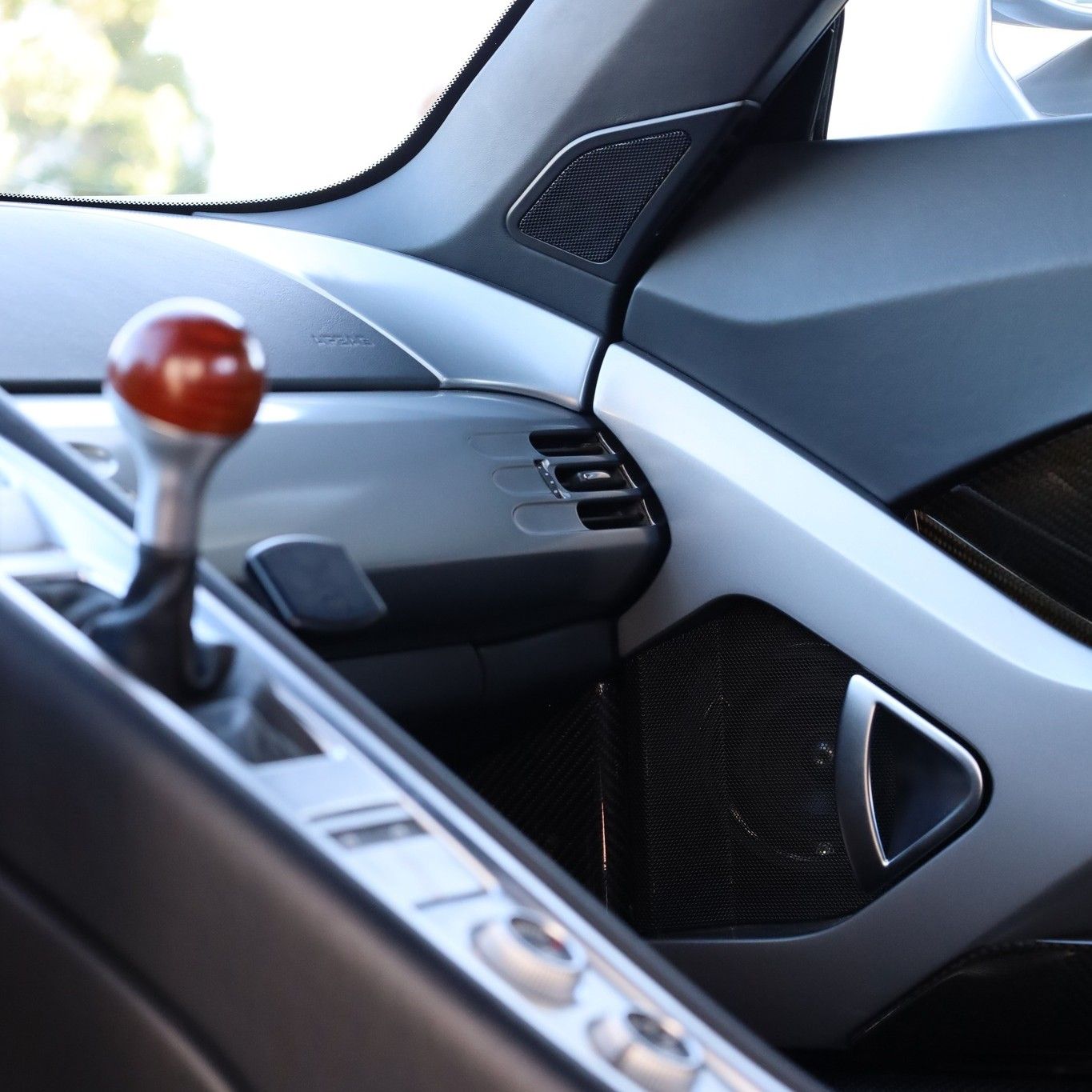 A close up of a car dashboard with a red shift knob