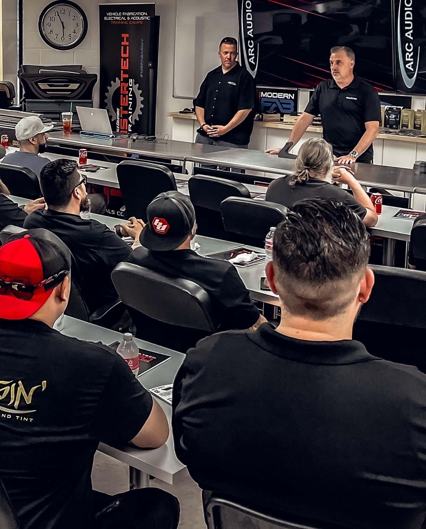 A group of men are sitting at tables in a classroom.