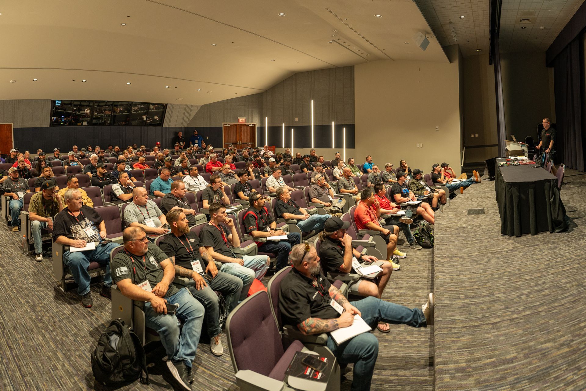 Audience in a large auditorium listens to a speaker at a conference.