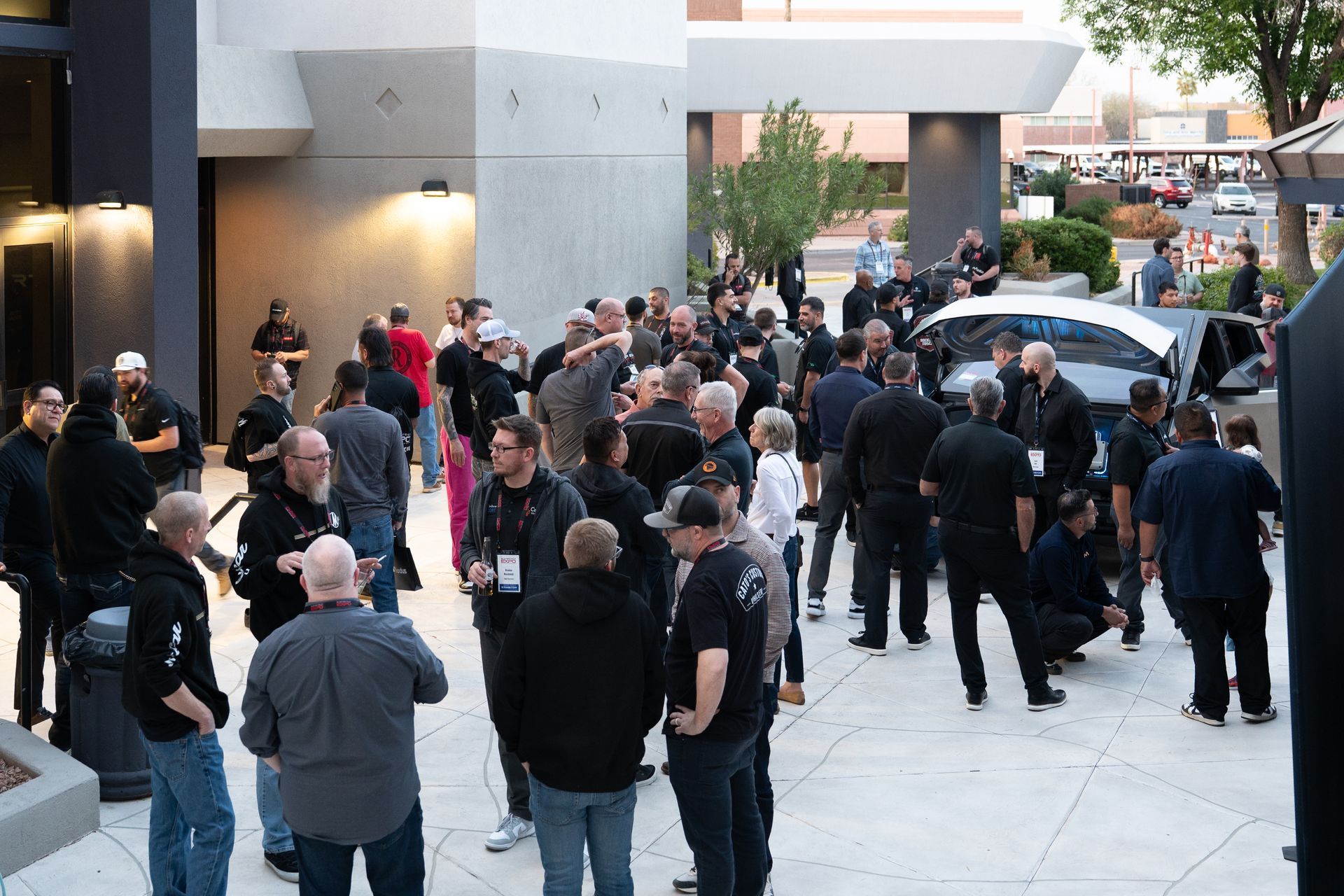 Group of people in dark clothing outside a building, socializing.