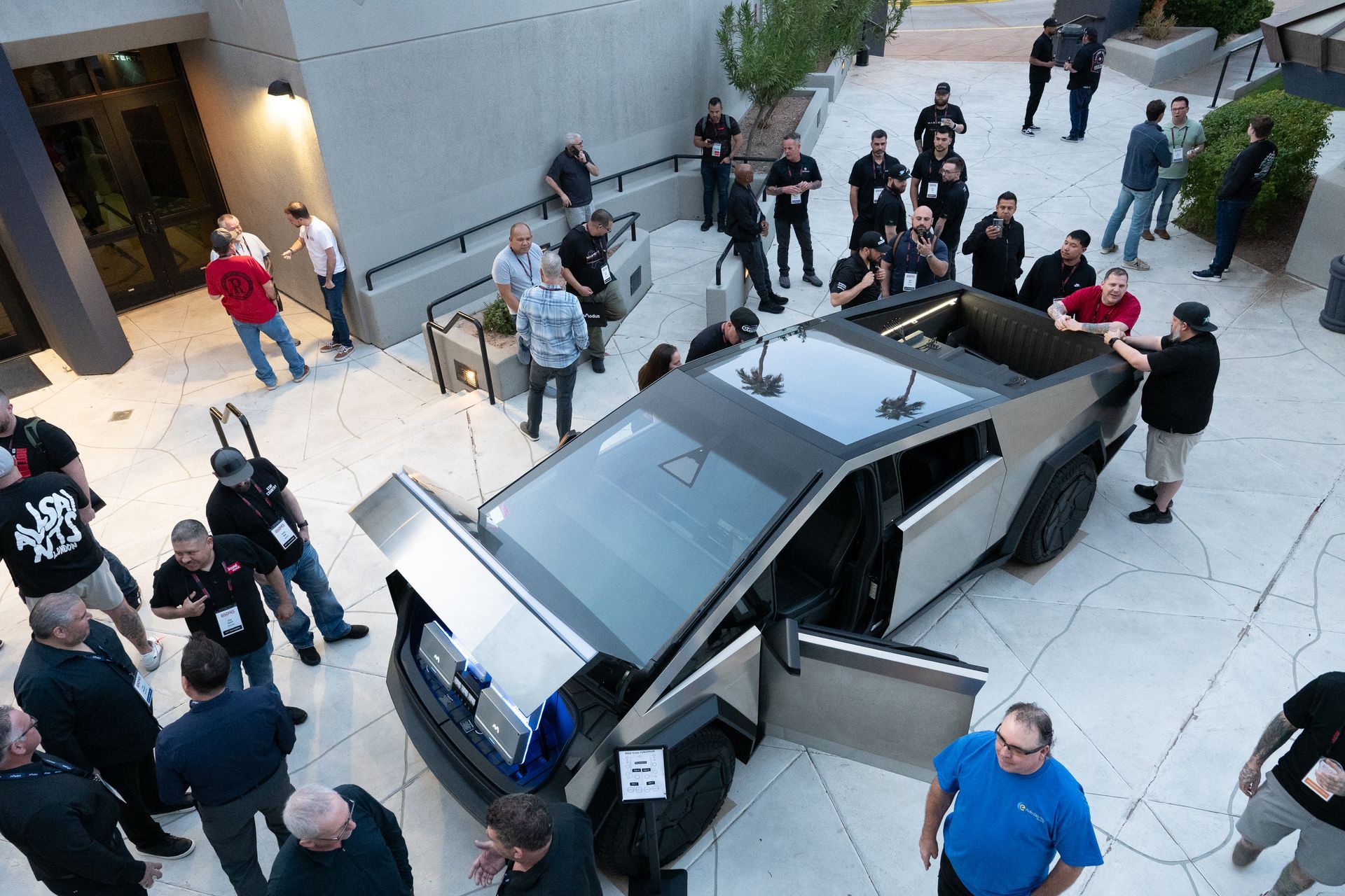 Tesla Cybertruck surrounded by people, doors open, outdoor setting, event.